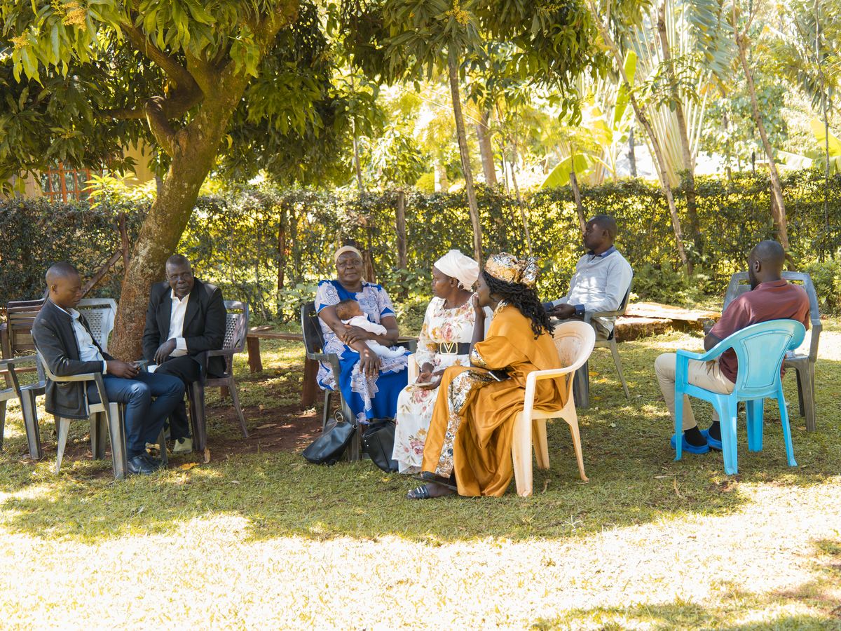 Community members seated in a circle under a tree