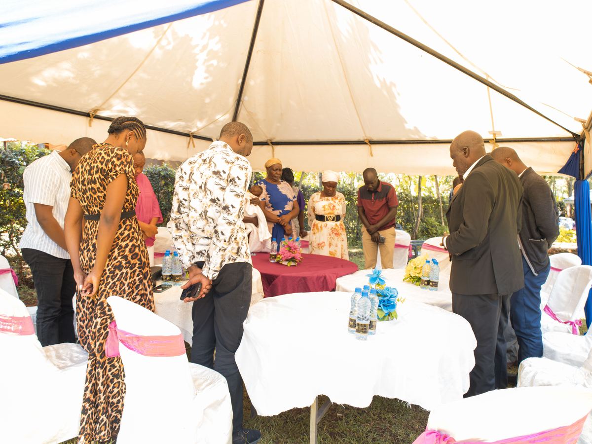 People standing together in prayer under a tent