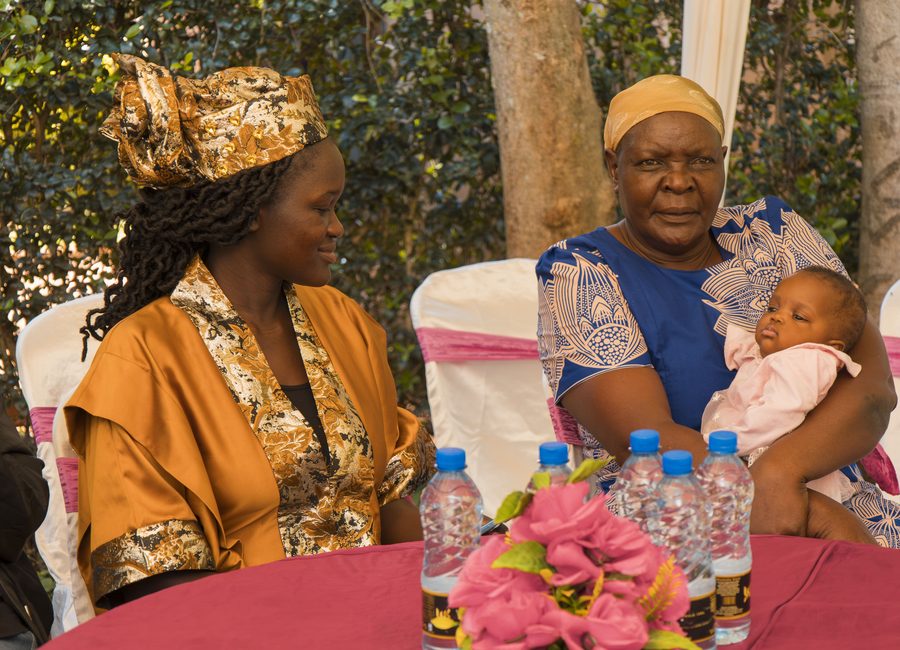 A grandmother holding a baby at a community gathering